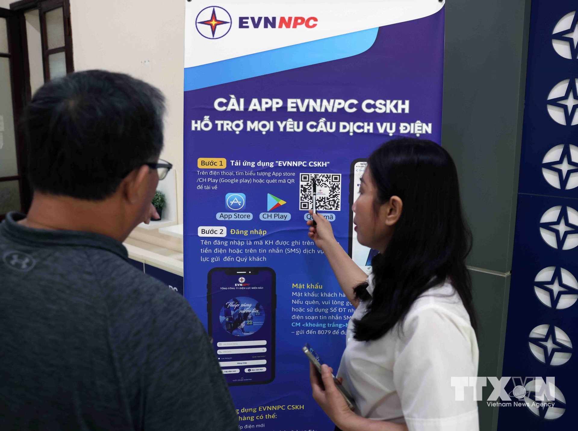 Nhân viên điện lực hướng dẫn người dân cài ứng dụng EVNNPC chăm sóc khách hàng, hỗ trợ mọi dịch vụ điện ở phòng giao dịch thành phố Thanh Hoá, tỉnh Thanh Hoá. (Ảnh: Vũ Sinh/TTXVN)